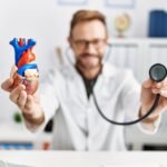 Middle age hispanic man wearing doctor uniform auscultating heart at clinic